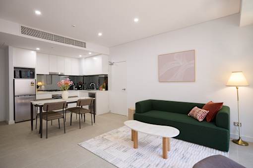 A modern living room with a green couch and a dining table.