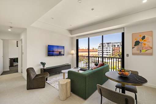 A living room with a green couch, a brown chair, a coffee table, and a painting on the wall.