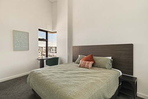 A bedroom with a large bed and a painting of Picasso on the wall.