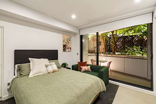 A bedroom with a green bed and a large window.