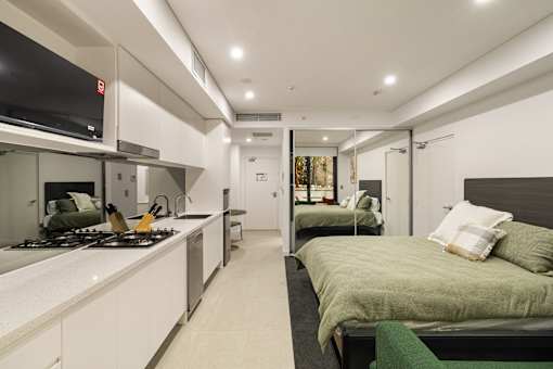 A modern kitchen with a green bed in the background.