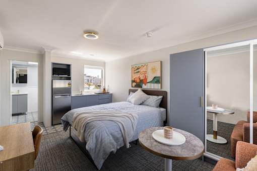 A bedroom with a bed, a table, and a chair.