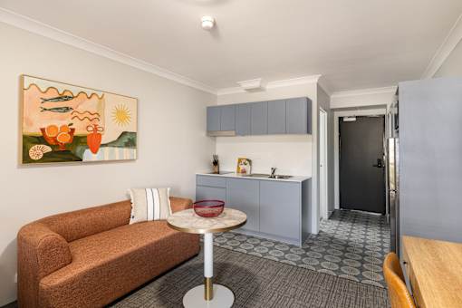 A living room with a brown couch and a painting on the wall.