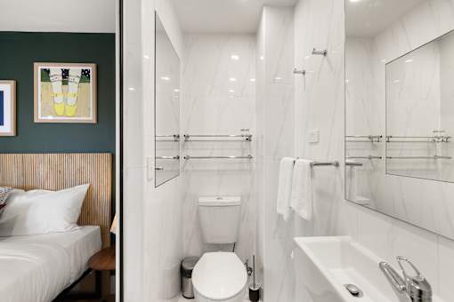 A white toilet sits in a bathroom with a white sink and a white bathtub.