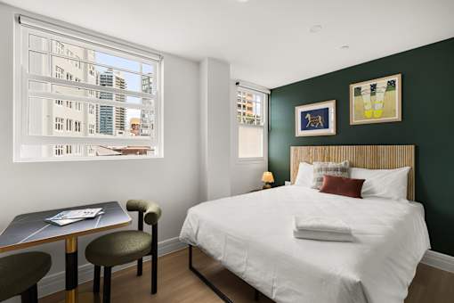 A bedroom with a large bed and a table with chairs.