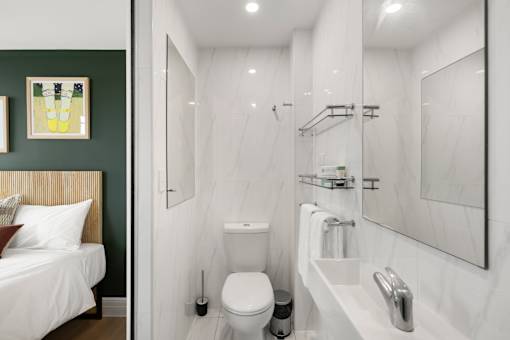 A white bathroom with a toilet, sink, and mirror.