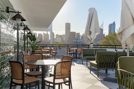 A patio with tables and chairs overlooking a city skyline.
