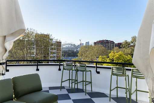 A balcony with a green couch and chairs overlooking a city skyline.