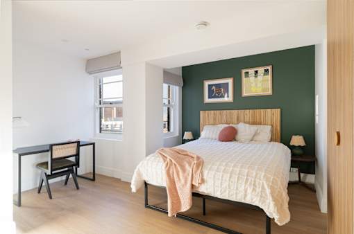 A bedroom with a bed, desk, and chair.