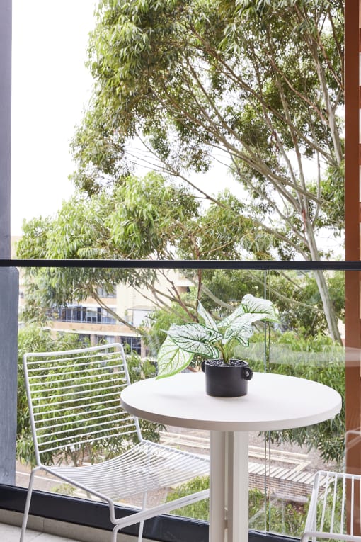 a small white table with a potted plant on a balcony
