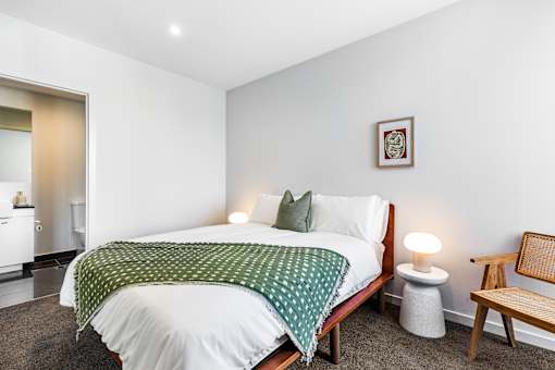 A bedroom with a bed, a chair, and a lamp.