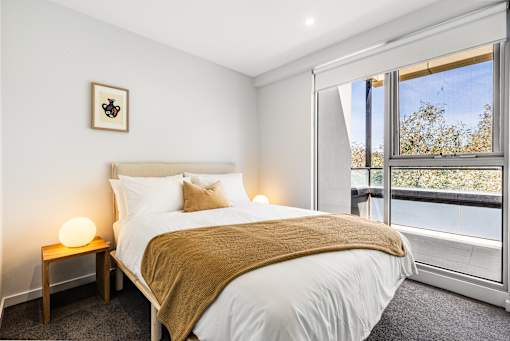 A bedroom with a large bed and a window overlooking trees.
