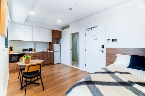 a bedroom with a bed and a kitchen with a small table