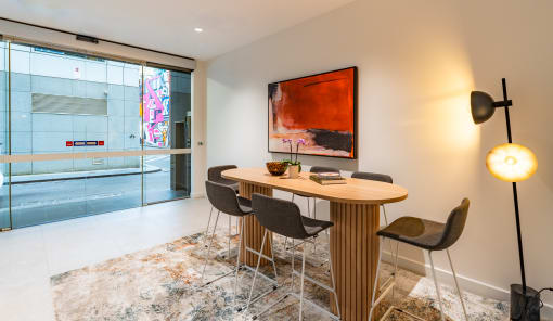 a dining area with a table and chairs and a painting on the wall