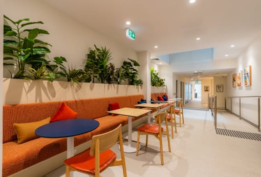 a lobby with orange couches and tables and chairs