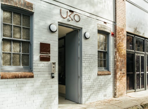 the front of a white brick building with an open door