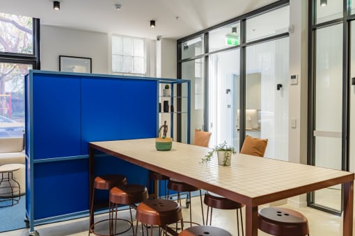 a communal table and stools in a room with glass doors