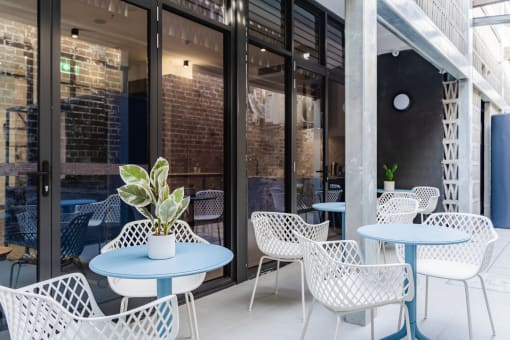 a patio with blue tables and chairs outside of a building