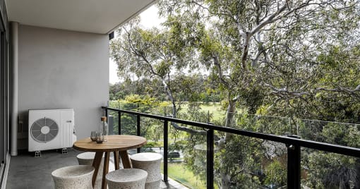 a balcony with a table and chairs and a view of trees