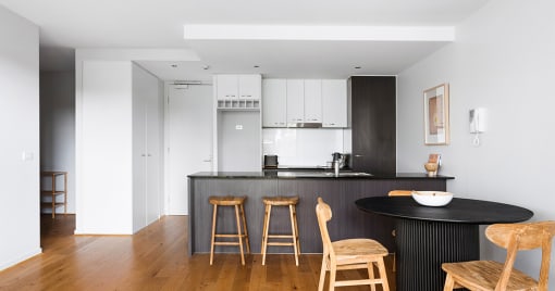 a kitchen with a black counter top and wooden bar stools