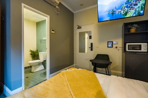 a bedroom with a bed and a tv in a room with a bathroom