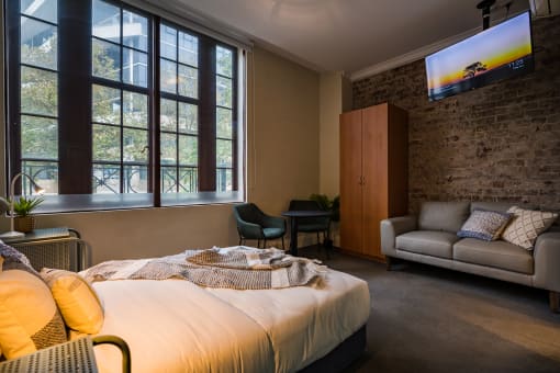 a bedroom with a bed and a couch and a window
