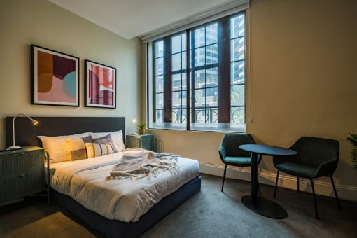 a bedroom with a bed and a window    and a table and chairs