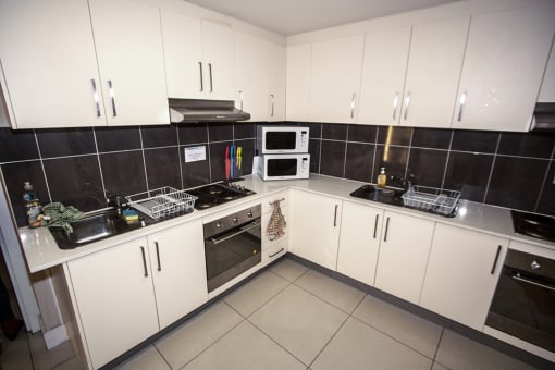 a kitchen with white cabinets and black tiles