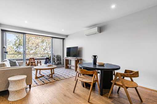 A living room with a black table surrounded by wooden chairs.