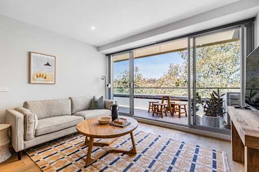 A living room with a couch, coffee table, and a view of trees outside.