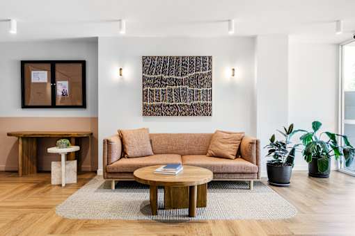 A living room with a brown couch, a coffee table, and a painting on the wall.