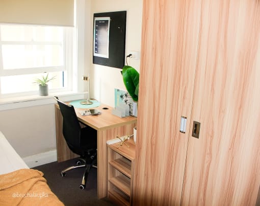 a small bedroom with a desk and a window