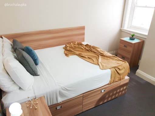 a bedroom with a bed with a wooden headboard and white bedding