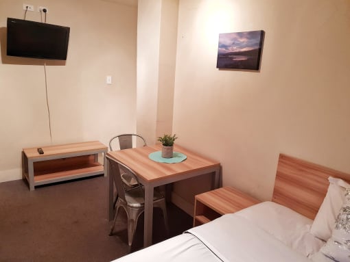 a small room with a bed and a desk and a television