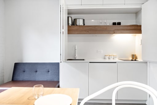 a kitchen with white cabinets and a table and a blue couch