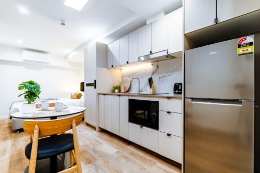 a kitchen with white cabinets and a table and a refrigerator