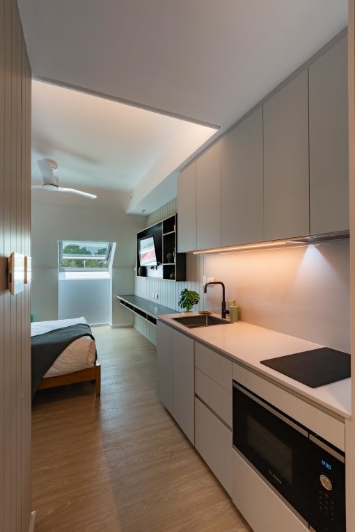 a kitchen with white cabinets and a sink and a bed