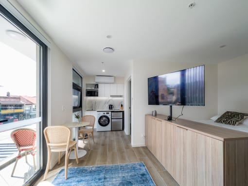 a living room with a tv and a kitchen with a table and chairs