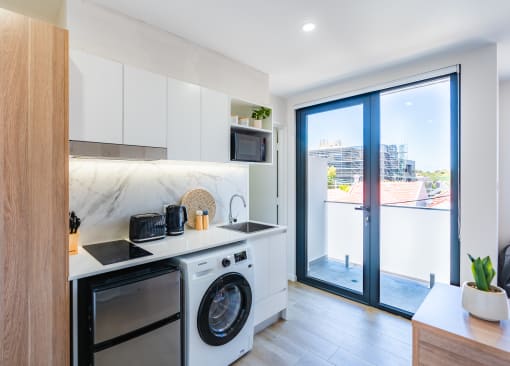 a kitchen with a washing machine and a door to a balcony