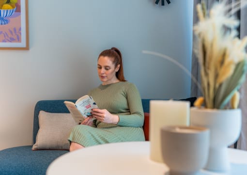 a woman sitting on a couch reading a book