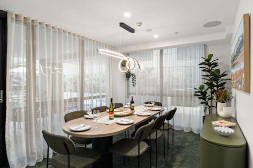 A dining room with a table set for two with a bottle of wine and a plate of food.