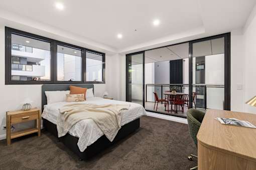 A bedroom with a large bed and a chair.