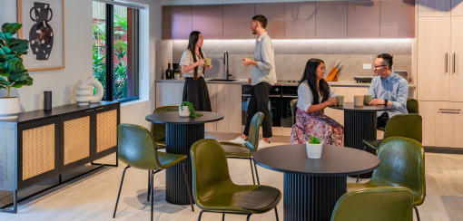 people in a kitchen and dining area with tables and chairs