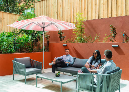 two people sitting on lounge chairs under an umbrella