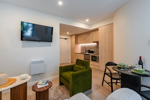 a living room and kitchen with a tv and a table and chairs