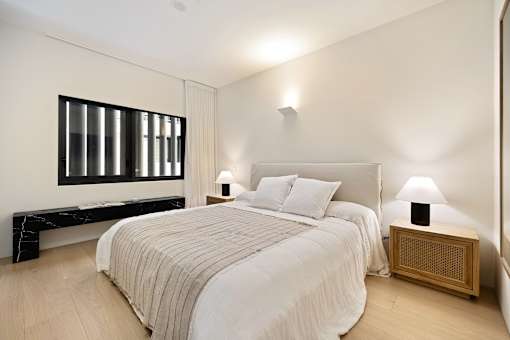 A bedroom with a large bed and a wooden nightstand.