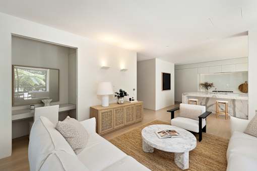 A modern living room with white furniture and a large window.