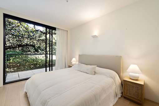 A bedroom with a large bed and a lamp on a side table.