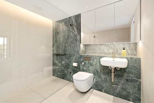 A modern bathroom with a toilet, sink, and marble countertops.