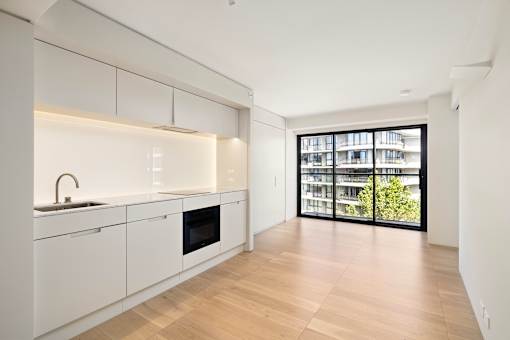 A modern kitchen with white cabinets and a wooden floor.